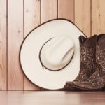 Cowgirl,Embroidered,Boots,And,White,Hat,On,Wooden,Background,-